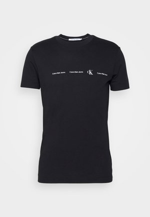 T-shirt noir à manches courtes et col rond, avec un petit texte blanc « Calvin Klein Jeans » et un logo « cK » centré sur la poitrine.