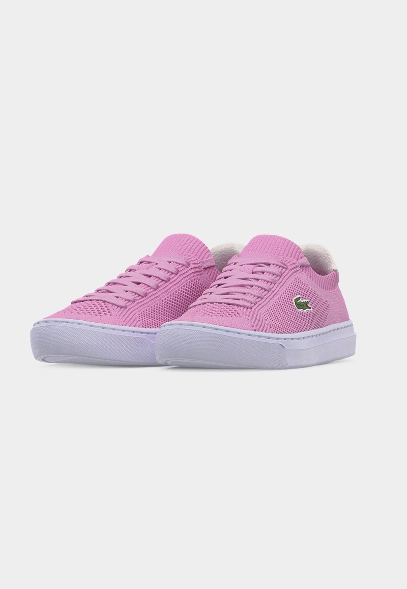 Paar flache, rosa Strick-Sneaker mit weißen Sohlen und grünem Krokodil-Logo an der Seite, leicht nach rechts geneigt auf weißem Hintergrund.