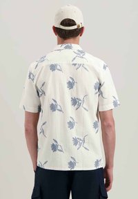 Camicia bianca a maniche corte con un motivo floreale blu; realizzata in un mix di cotone e lino con una vestibilità comoda e dettagli sul dorso.