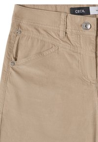 Pantalon en velours côtelé beige avec poches avant, passants de ceinture, fermeture par bouton métallique et coutures visibles.