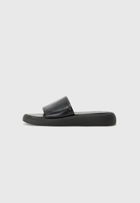 Sandale noire à glissière avec un dessus en cuir doux et une semelle en caoutchouc plate et texturée. Présente un design minimaliste et une large sangle avant.