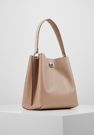 Beige leren handtas met een textuur, voorzien van een enkele schouderriem en een zilveren draaisluiting, getoond op een witte ondergrond.