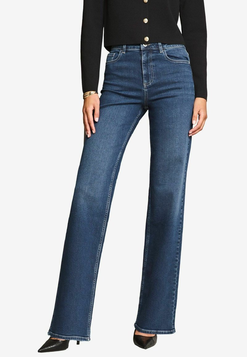 Temno modri široki jeans iz denima z visokim pasom, ki vključujejo sprednje žepke, šive ob straneh in raztrgan rob.