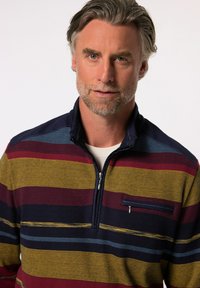 Sweter w paski z ośmioma poziomymi paskami w kolorze granatowym, bordowym, żółtym i turkusowym. Teksturowany materiał z zamkiem błyskawicznym przy kołnierzu oraz kieszonką na piersi.