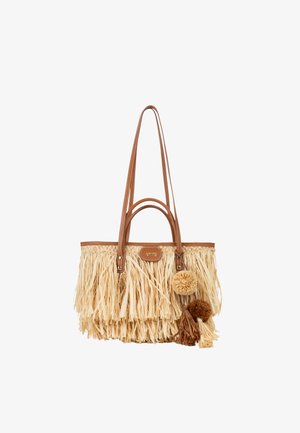 Sac cabas en paille tressée beige et fauve avec de longues anses en cuir et des pompons décoratifs ainsi que des glands sur le côté.