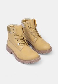 Paire de bottes de travail beiges à lacets avec col rembourré et semelles robustes sur fond blanc.