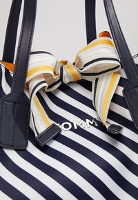 Borsa a strisce blu e bianca con manici in pelle nera, caratterizzata da un fiocco a strisce gialle, bianche e nere e dal logo metallico "TOMMY".
