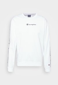 Witte sweatshirt met lange mouwen, ronde hals, zwart Champion-logo op de borst en patroonaccenten langs de mouwen. Zachte stof.