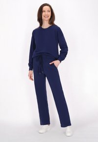 Sudadera azul marino y pantalones jogger a juego, confeccionados en una tela suave. La sudadera tiene un escote redondo y los pantalones cuentan con una cinturilla elástica con cordones.