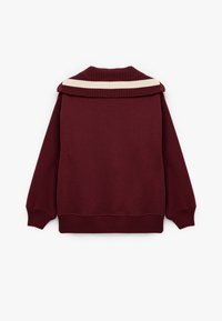 Sudadera burdeos con cuello de canalé que presenta una franja horizontal crema, mangas largas con puños de canalé y un corte relajado.