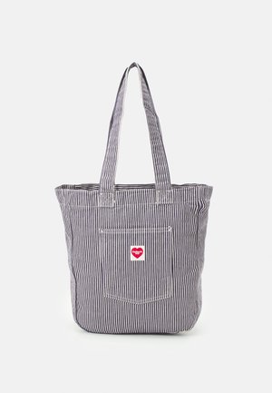 Torba na ramię z paskiem, wykonana z tkaniny w paski, z dwoma długimi uchwytami i zewnętrzną kieszenią z małą czerwoną i białą naszywką z logo.