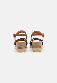 Brown and navy platform sandals with three straps, adjustable ankle buckle, and textured beige sole featuring white stitching detail.