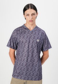 Tričko s výstrihom do V v tmavofialovej látke so vzorom opakujúcich sa bežcov, krátkymi rukávmi a malým logom na hrudi.