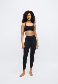 Schwarzes Sport-BH- und Leggings-Set mit figurbetontem Design, glatter Textur, verstellbaren Trägern und hohem Bund, ohne sichtbare Muster.