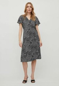 Rochie neagră, cu un model cu buline albe, având mâneci scurte și volanate și o fustă până la genunchi. Pur și simplu cu sandale negre cu toc.