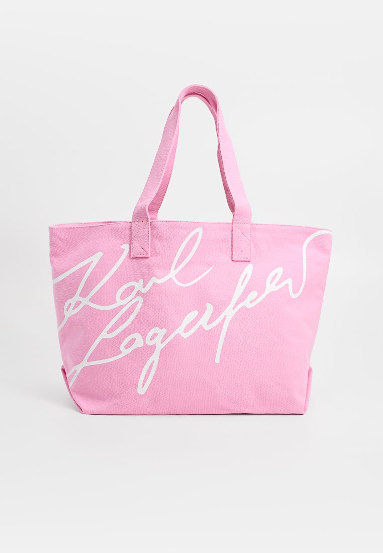 Sac en toile rose avec deux poignées et texte en cursive blanche sur le devant.