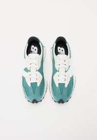 Le scarpe da atletica turchese e bianche presentano una tomaia in suede e tessuto, chiusura con lacci e suola testurizzata con un accento in gomma nera.