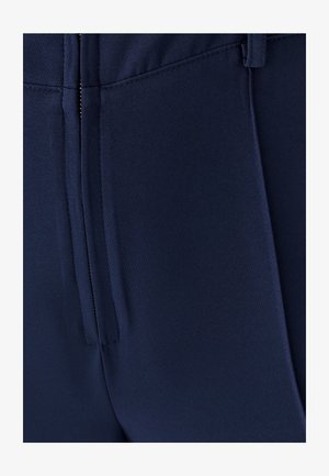 Granatowe spodnie dopasowane o gładkiej fakturze, z zamkiem błyskawicznym, kieszeniami z przodu i zakładkami dla uzyskania strukturalnego wyglądu.