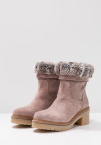 Suede ankle boots in soft pink with faux fur lining at the cuff. Chunky heel and textured rubber sole for traction.
