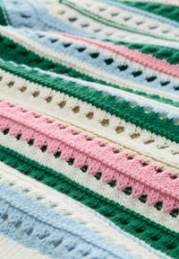 Gehaakte deken met afwisselende horizontale strepen in groen, roze, blauw en wit, met een gestructureerd patroon en opengewerkte details.