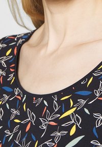 Black fabric with a round neckline featuring colorful floral patterns in yellow, red, and blue, outlined in white thread.