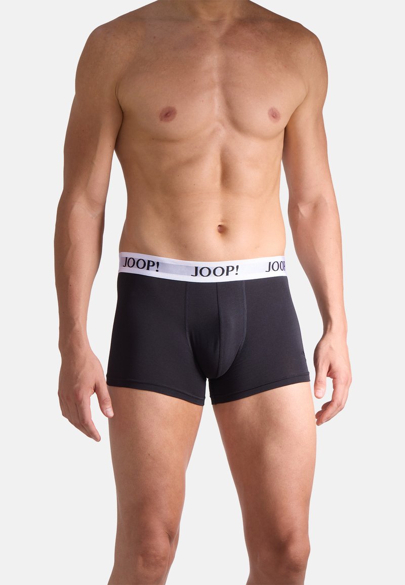 Torso masculino sin camiseta que lleva puestos bóxers ajustados negros con una cintura blanca que muestra el logo "JOOP!".