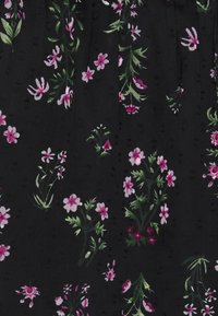 Tissu noir avec de petits groupes de fleurs roses et blanches ainsi que des feuilles vertes formant un motif floral dispersé.