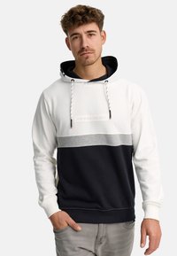 Hættebluse med en farveblokdesign i hvid, grå og marineblå, lavet af blødt stof med snore og et trykt mærke.