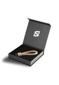 Tan woven leather keychain with a black accent in a black presentation box featuring a white logo on the lid.