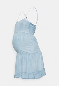 Vestido de maternidade em denim com alças finas ajustáveis, comprimento midi com evasé e cintura franzida. A cor é azul claro com uma textura suave.