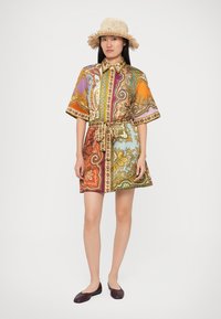 Sukienka z krótkim rękawem z kolorowym wzorem paisley, z paskiem w talii i kołnierzykiem. Wykonana z lekkiego materiału. Noszona z kapeluszem ze słomy i balerinami.