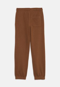 Brune bomullssweatpants med elastisk belte, innsnevrede mansjetter og en baklomme. Jevn tekstur og minimalistisk design.