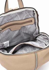 Mochila de cuero perforado beige con cierre de cremallera, que cuenta con un forro gris con estampado y un bolsillo interior con cremallera.