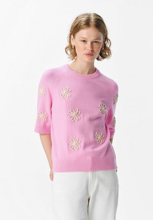 Helles rosa, gestricktes Sweatshirt mit kurzen Ärmeln, verziert mit gestickten weißen Blumen. Mit geripptem, rundem Ausschnitt und Saum. Weiche Textur.