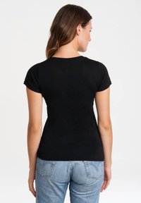 Black short-sleeve t-shirt with a fitted design, featuring a rounded neckline and smooth texture, paired with light blue jeans.
