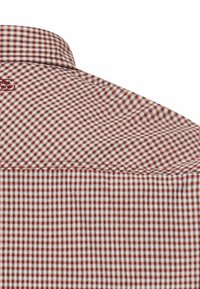 Kołnierz i górna część pleców koszuli w kratę z małymi czerwonymi, białymi i niebieskimi kwadratami na białym tle.