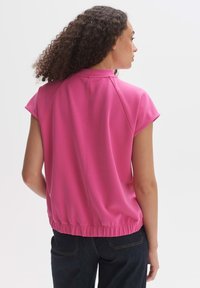 Korte mouwen, roze top met hoge kraag en elastische zoom, gemaakt van soepel materiaal en met subtiele schoudernaden. Casual ontwerp.