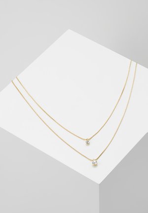 Gul dobbelt-streng halskæde prydet med to hængende krystaller, en større og en mindre, med en delikat kæde og glat tekstur.