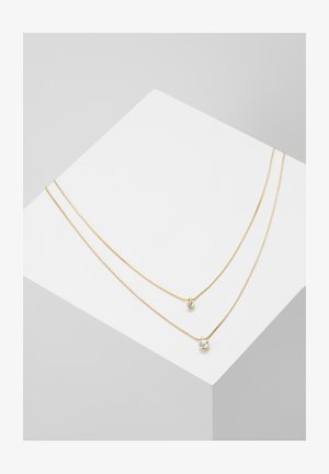 Gul dobbelt-streng halskæde prydet med to hængende krystaller, en større og en mindre, med en delikat kæde og glat tekstur.