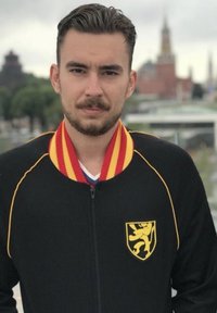 Zwarte ritssluiting jack met rode en gele kraag, voorzien van een gele leeuw-embleem op de linkerborst en contrasterende gele stiksels.