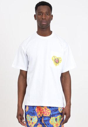 T-shirt en coton blanc à manches courtes et une poche, ornée d'un design coloré en or, rose et bleu. Coupe décontractée.