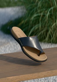 Sandale à talon ouverte en cuir bleu marine, avec une semelle intérieure en tan rembourrée, une semelle en caoutchouc noir et des détails de coutures blanches sur le côté.