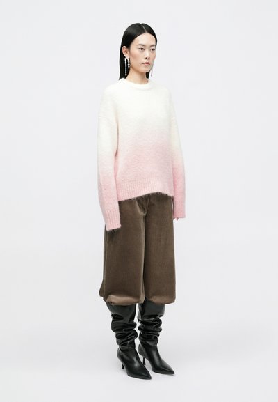 Lett strikket sweater, der går fra hvid til pink, kombineret med brune kordfløjl højtaljede bukser og sorte løse knæhøje støvler.