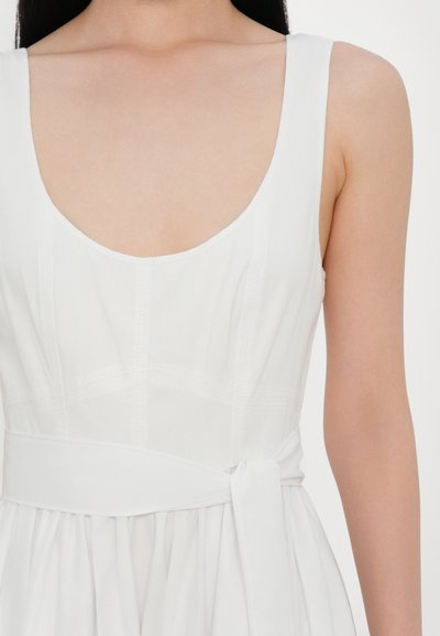 Weißes Kleid mit weitem Ausschnitt, breiten Trägern und gebundenem Taillengürtel. Glatte Textur mit vertikalen Nahtdetails.