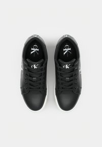 Svarta lädersneakers med rund tå, vit gummisula och snörning med band. Har logotyp på tungan och sidan, slät textur och minimalistisk design.