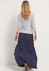 Randig långärmad topp i vitt och marinblått, parat med en svepande marinblå maxikjol, med enkla linjer och en avslappnad passform.