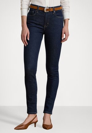 Mørkeblå slim-fit jeans med let stræk, der har diskrete kontrastsømme og frontlommer, parret med et brunt bælte og slingback hæle.