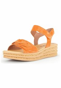 Orange ruskinds kilehæle med en bred rem, dekorativ syning og en lagdelt korksål. Har en justerbar ankelrem for støtte.