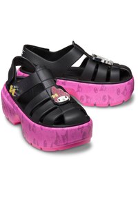 Infradito in plastica nera con design aperto, dotate di suole con motivo rosa e un accento di personaggio sulla cinghia. Suola spessa per un'altezza aggiuntiva.