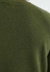 Pull en tricot vert foncé, avec un col côtelé et une texture à finition lisse. Pas de motifs visibles ni de détails métalliques.